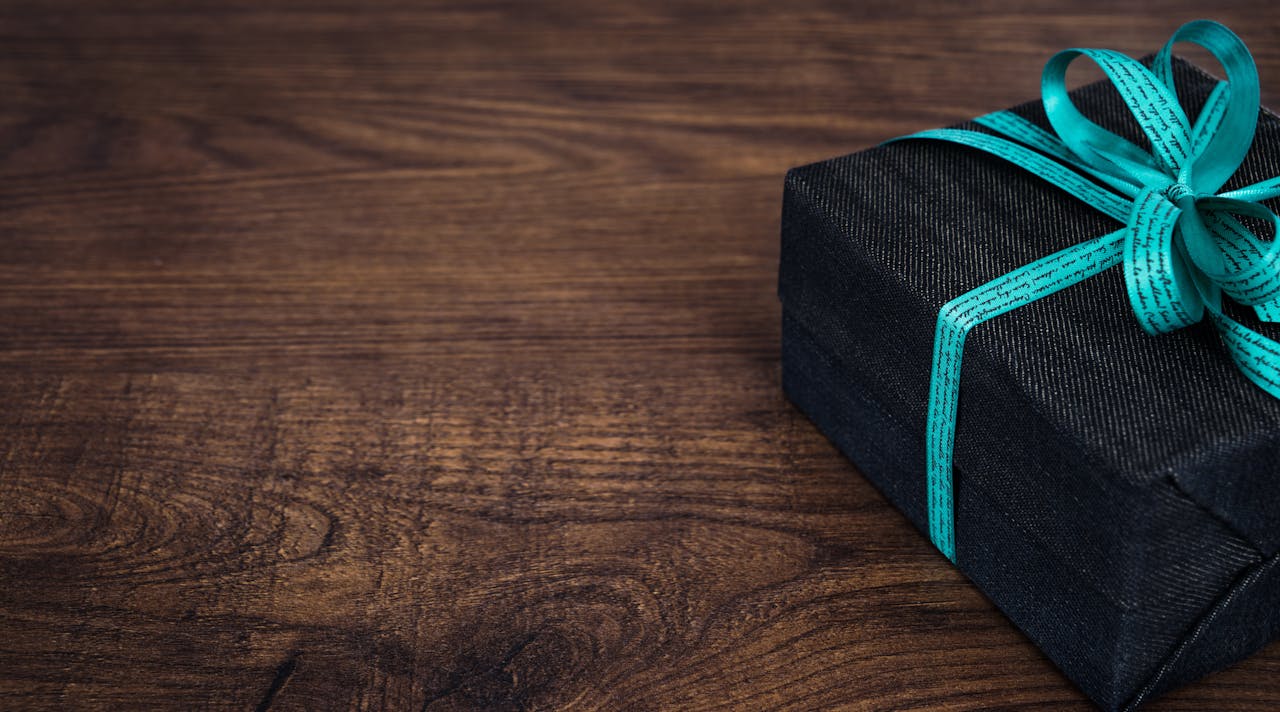 gallery-01 A stylish black gift box with blue ribbon on a wooden table, perfect for celebrations.