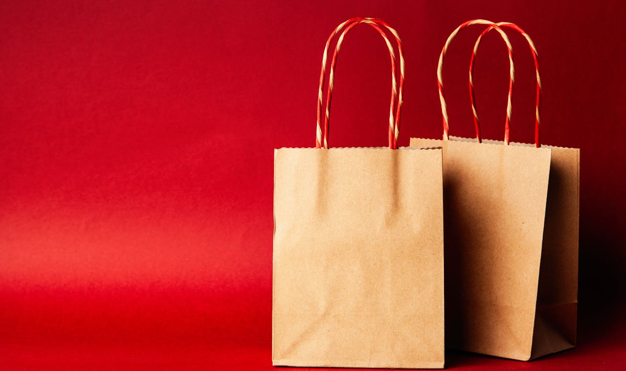 gallery-03 Simple brown paper bags with handle on a festive red backdrop, perfect for Christmas.